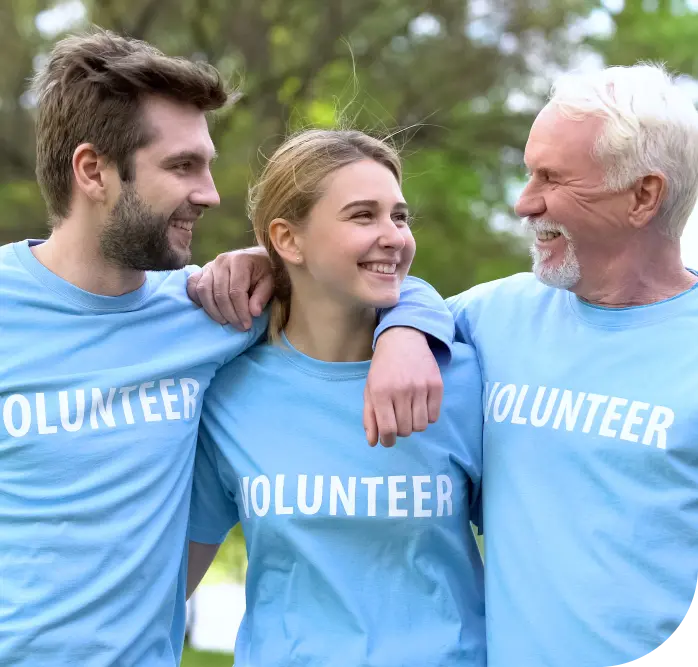 Three happy people linked shoulder to shoulder wearing volunteer t-shirts.