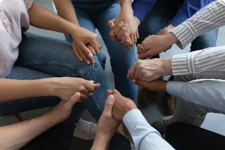 People in support group circle holding hands.